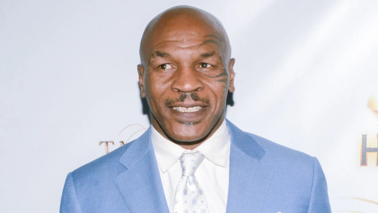 Mike Tyson vestido de saco azul, camisa blanca y corbata blanca.