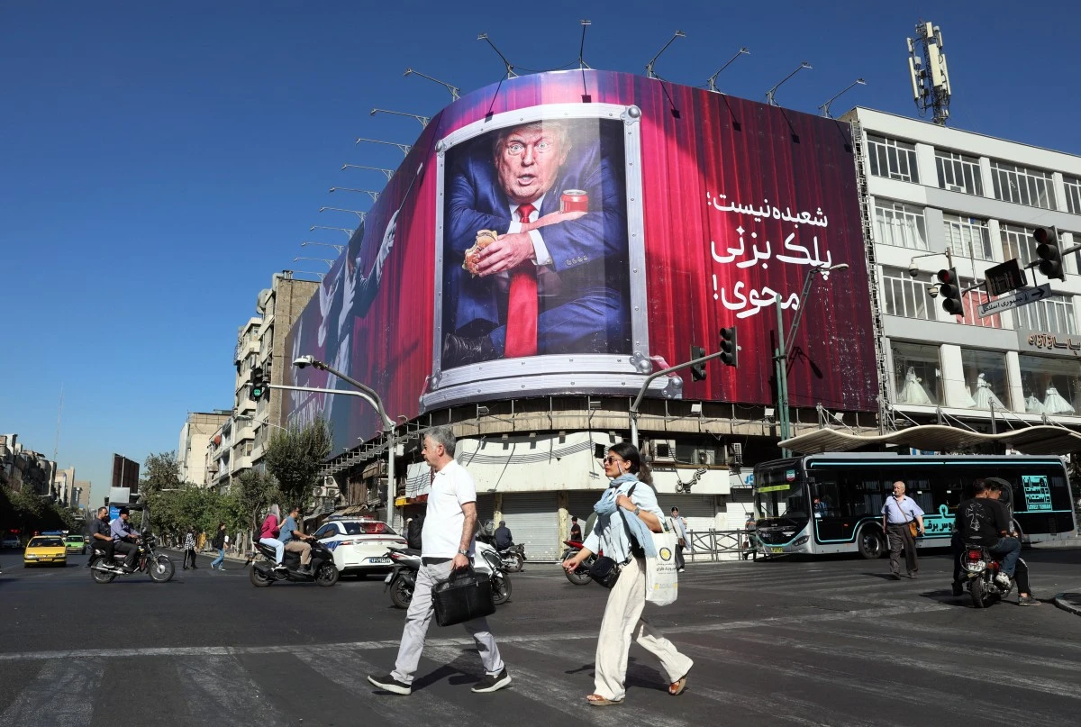 Imagen de personas caminando y de fondo rótulo de Trump