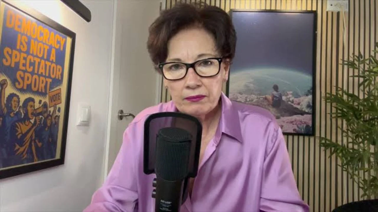 Analista Juana Flores frente a un micrófono, vestida con una camisa de botones color lila.