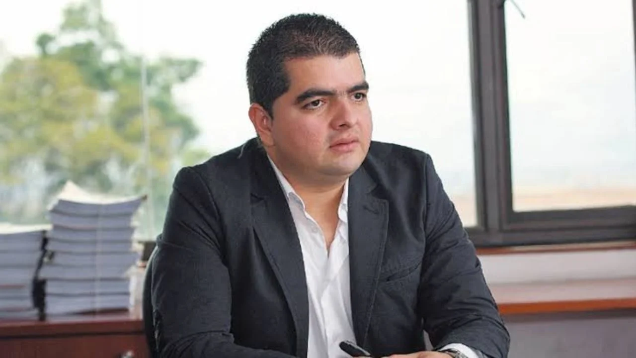 Julián Bedoya sentado y vestido con saco y camisa de botones