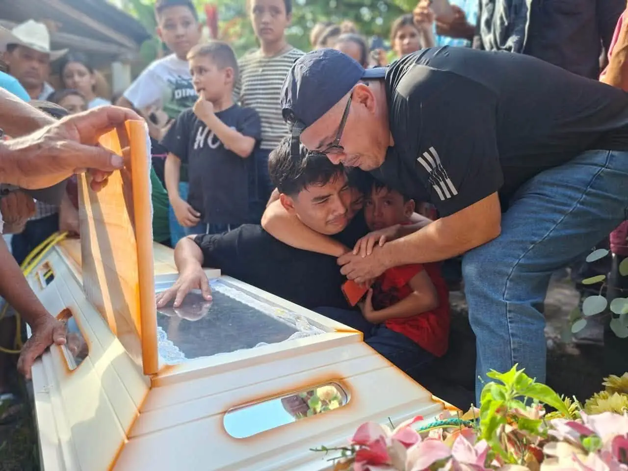 Marvin junto a sus hijos llorando sobre el ataúd de Endy Jiménez