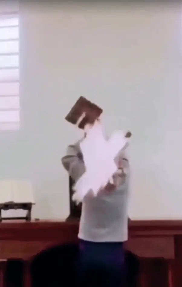 momento en que una cruz de madera cae sobre un sacerdote colombiano